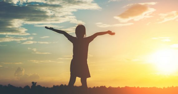 Silhouette of little girl raising hand to freedom happy time